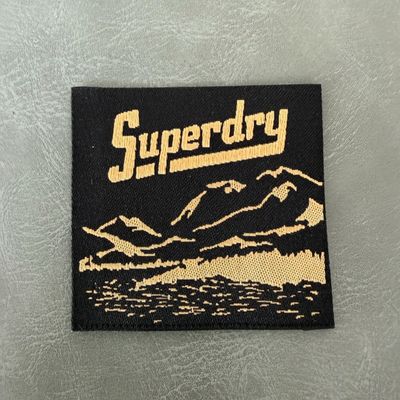 Jacquard woven label LBL 0046 5 x 5 cm – black background with gold letters, premium design, soft style, with logo